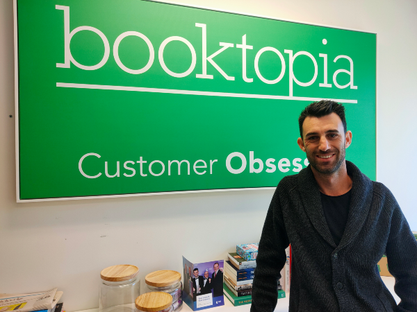 Wayne Baskin, Booktopia, standing in from of booktopia sign subtitled 'Customer Obsessed'